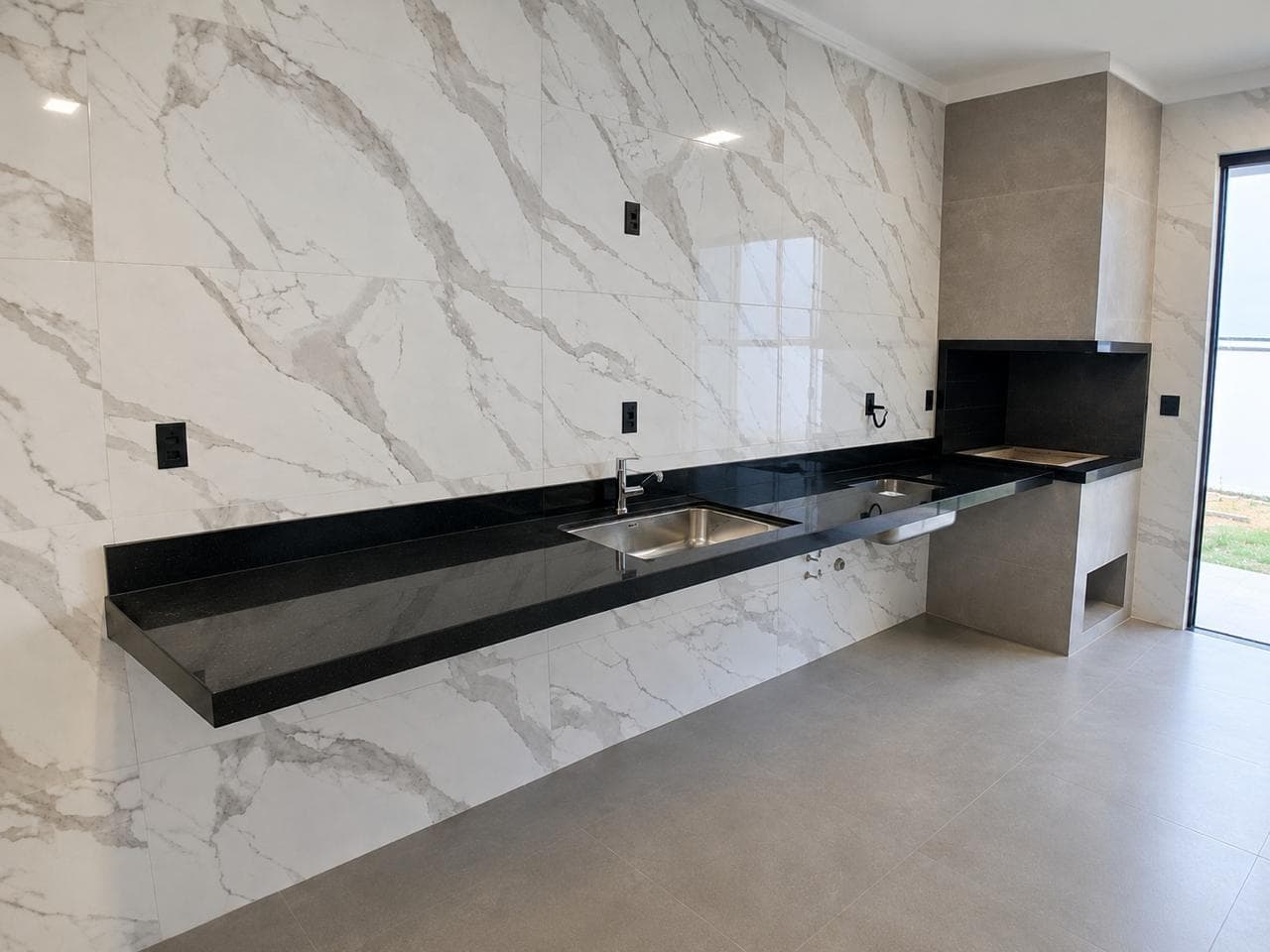 Cozinha Integrada com Bancada Contínua em Granito Preto e Parede Revestida